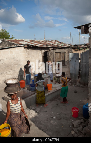 Bewohner von Keko Mwanga, einem Slum in Dar Es Salaam, Tansania, Ostafrika, sammeln Sie Wasser aus einem Hahn in der Gemeinschaft. Stockfoto