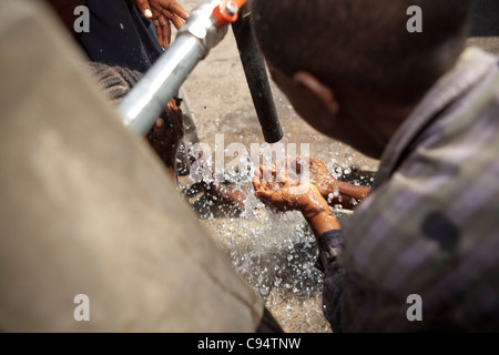 Kinder trinken Wasser aus einem Bohrloch in Dar Es Salaam, Tansania, Ostafrika. Stockfoto