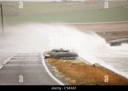 Sturm angetrieben Wellen über Landstraße am Deerness Orkney Festland, Schottland, UK. Stockfoto