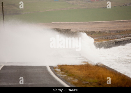 Sturm angetrieben Wellen über Landstraße am Deerness Orkney Festland, Schottland, UK. Stockfoto