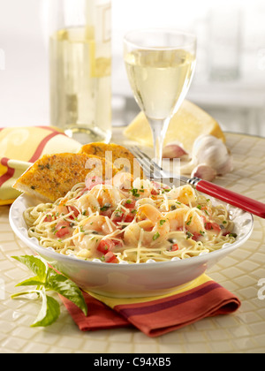 Shrimp Scampi Nudeln garniert mit Parmesan-Käse, serviert mit Knoblauch Brot und Weißwein Stockfoto
