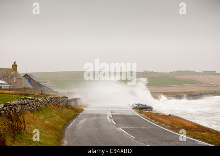 Sturm angetrieben Wellen über Landstraße am Deerness Orkney Festland, Schottland, UK. Stockfoto