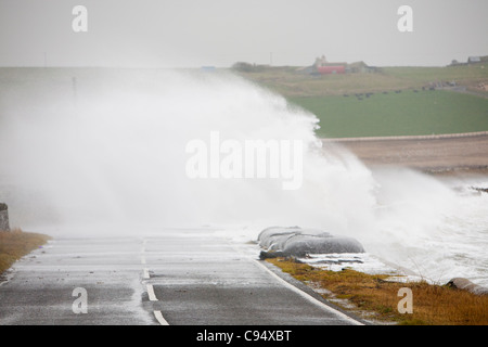 Sturm angetrieben Wellen über Landstraße am Deerness Orkney Festland, Schottland, UK. Stockfoto