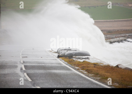 Sturm angetrieben Wellen über Landstraße am Deerness Orkney Festland, Schottland, UK. Stockfoto