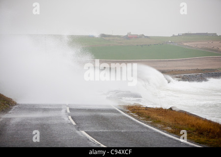 Sturm angetrieben Wellen über Landstraße am Deerness Orkney Festland, Schottland, UK. Stockfoto