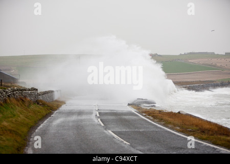 Sturm angetrieben Wellen über Landstraße am Deerness Orkney Festland, Schottland, UK. Stockfoto