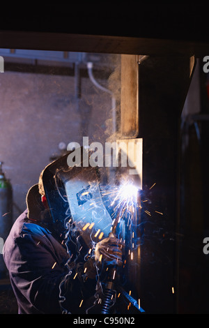 Arbeiter im Stahlwerk mit Schweißen Maske, Werkzeuge und Maschinen auf Metall. Vertikale Form, Seitenansicht, Textfreiraum Stockfoto