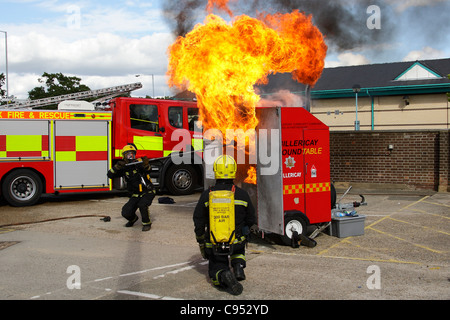 Feuerwehrleute zeigen die Auswirkungen des strömenden Wassers auf ein brennendes Öl-Feuer in der Küche Stockfoto