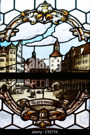 Ein Fenster aus Buntglas aus dem neuen Rathaus mit einer Illustration von der Maria-Platz in München. Stockfoto
