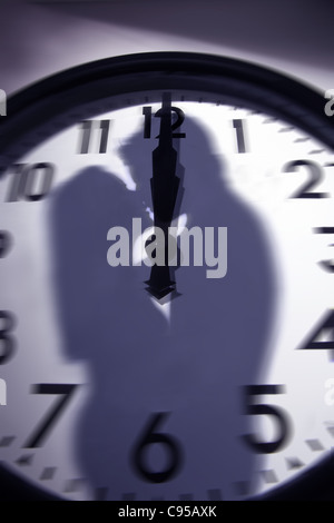 Silhouette paar küssen um Mitternacht auf einem Taktgebergesicht überlagerten Stockfoto