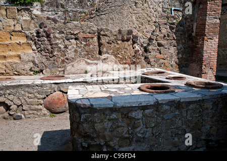 Die gefliesten Mauerwerk-Theke mit Tonkrügen (Dolia) eingebettet in eine typische ausgegrabenen Thermopolium, Herculaneum Stockfoto