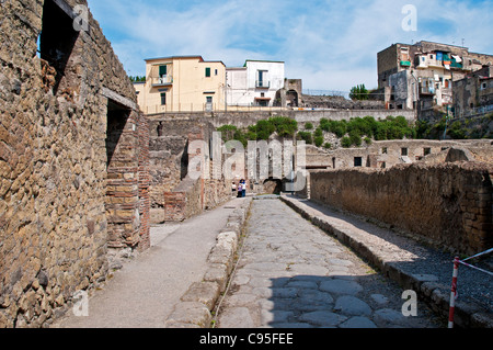 Moderne Häuser von Ercolano schauen hinunter auf die ausgegrabenen Ruinen der Gebäude entlang einer typischen gepflasterten Straße in Herculaneum, Stockfoto