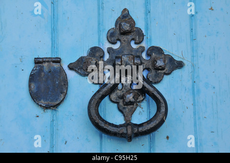 Eine blaue Holztür mit einem reich verzierten und alte Türgriff und Klopfer mit Schlüsselloch und Deckel. Stockfoto