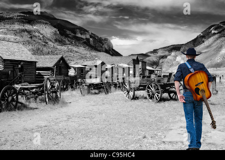 Bild suchen Sie die Hauptstraße entlang der alten Trail Town in Cody, Wyoming als Cowboy mit einer Gitarre über seinen Rücken geschlungen Aways geht. Stockfoto