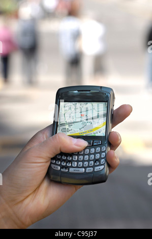 Benutzer mit BlackBerry 8310 Curve Smartphone auf der Straße, die GPS-Stadt Karte zeigt aktuellen Standort anzeigen Stockfoto