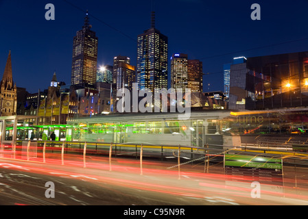 Verkehr und Straßenbahn Lichtspuren auf Swanston Street mit Skyline der Stadt im Hintergrund.  Melbourne, Victoria, Australien Stockfoto