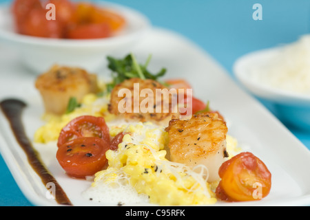 Safran-Risotto mit gegrillten Jakobsmuscheln und Cherry-Tomaten-sauce Stockfoto