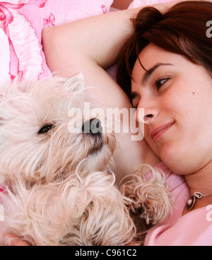 Westie neben Frau im Bett schlafen. Stockfoto