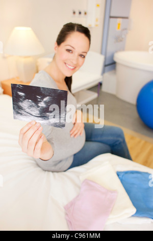 Schwangere Frau mit ihrem Baby-Scan in einem Raum bei einer Hausgeburt. Stockfoto