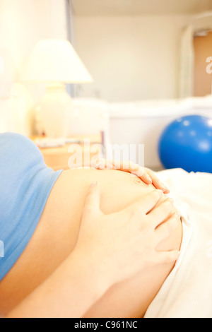 Hausgeburt. Nahaufnahme der Bauch einer schwangeren Frau in einem Raum bei einer Hausgeburt. Stockfoto