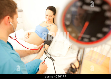 Geburtshilfliche Untersuchung. Eine schwangere Frau Blutdruckmessung bei einer Hausgeburt Hebamme. Stockfoto