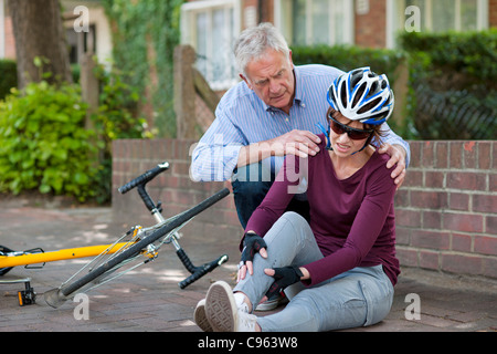 Fahrradunfall. Menschen helfen, einen Radfahrer, der vom Fahrrad gefallen ist. Stockfoto