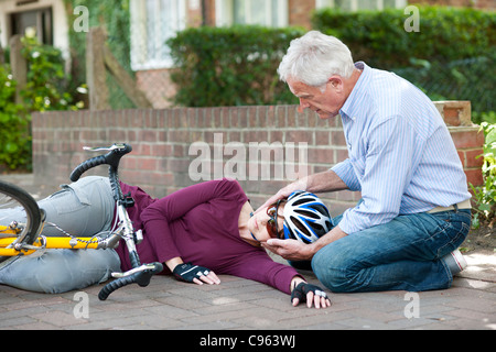 Fahrradunfall. Menschen helfen, einen Radfahrer, der vom Fahrrad gefallen ist. Stockfoto