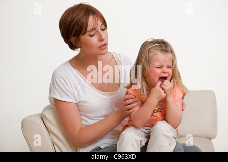 Kleinkind weint auf der Mutter Schoß. Stockfoto