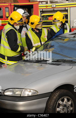 Feuerwehrführungskräfte Dienst vorbereiten, ohne ein Auto nach einer Kollision Kollision Opfer zu schneiden. UK Dezember 2010. Stockfoto