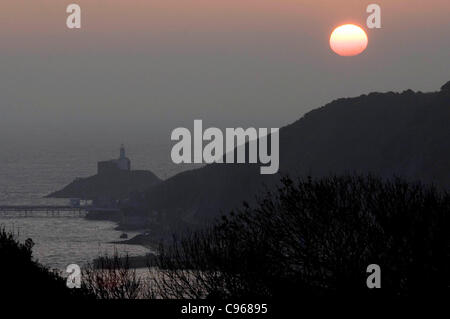 Die Sonne geht aus dem Nebel als Morgendämmerung bricht über die Mumbles-Leuchtturm in der Nähe der kleinen Dorf Mumbles, in der Nähe von Swansea, Großbritannien, auf Dienstag, 15. November 2011. Stockfoto