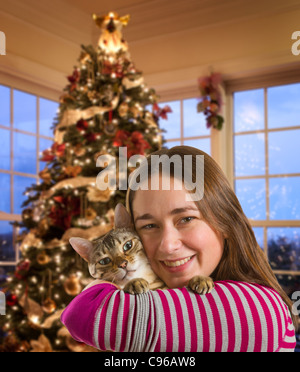 Junge Bengal Kätzchen am Arm der jungen Frau vor hell statt beleuchtete Christmas tree Stockfoto