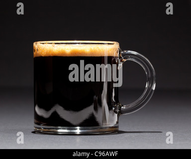 Schwarz mit berauschenden Schaum in einem Glas Becher oder einer Tasse Kaffee Espresso Stockfoto