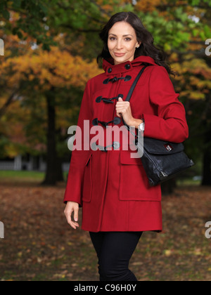 Schöne junge Frau trägt einen roten Mantel Stand auf einer Stadtstraße im Herbst