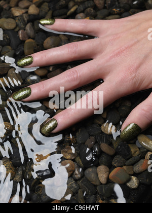 Lizenz erhältlich unter MaximImages.com Nahaufnahme der Frauenhand mit grünem, feinem nagellack in Wasser Stockfoto