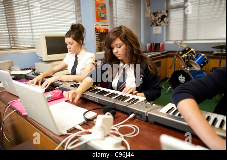 Zwei Teenager Mittelschule Mädchen spielen elektronische digitale Tastaturen in einer Musik-Technologie-Klasse Lektion Wales UK Stockfoto