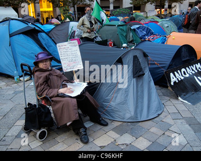 Demonstranten und Zelten außerhalb von St. Pauls Cathedral London mit weibliche Person und Plakat antikapitalistische Demonstration 2011 Stockfoto