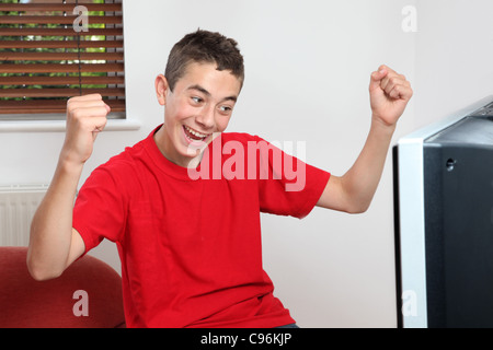 Junge Männchen beobachten und Jubel Sport im Fernsehen Stockfoto