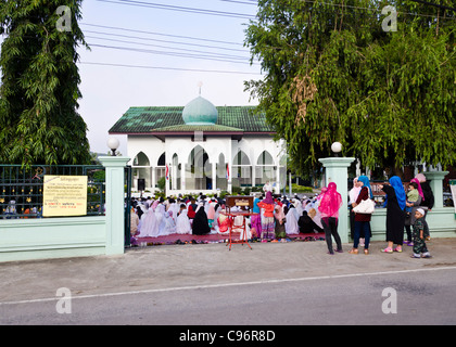 Moschee mit Outdoor-Gottesdienst in der Sitzung. Dutzende von Menschen sitzen auf Boden in muslimischen Kleid in Nordthailand Stockfoto