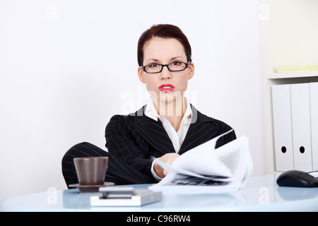 Ziemlich kaukasischen mad Geschäftsfrau im Büro sitzen den Anzeigen von Dateien. Stockfoto