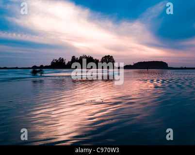 Sonnenuntergang bei Surfern in Ferne am South Chesterman Beach, Vancouver Island, British Columbia, Kanada Stockfoto