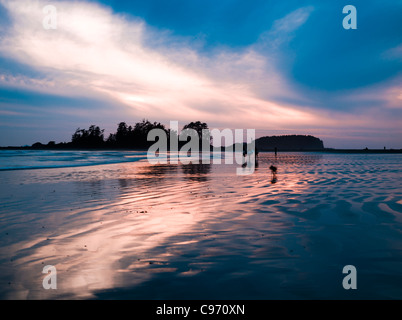 Sonnenuntergang bei Surfern in Ferne am South Chesterman Beach, Vancouver Island, British Columbia, Kanada Stockfoto