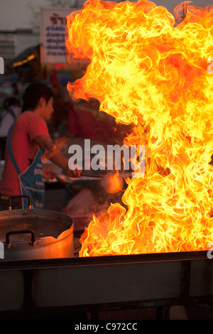 Flammen aus dem Wok; frisch zubereitetes Essen an Hua Raw Nachtmarkt in Ayutthaya, Thailand Stockfoto