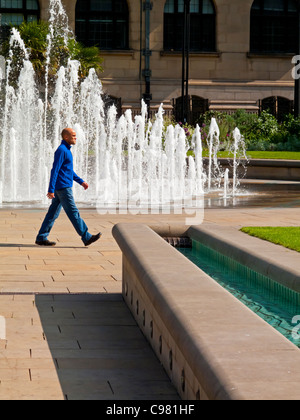 Mann zu Fuß vorbei an Brunnen und Wasser-Funktion in Sheffield Peace Gardens in Sheffield City Centre South Yorkshire England UK Stockfoto