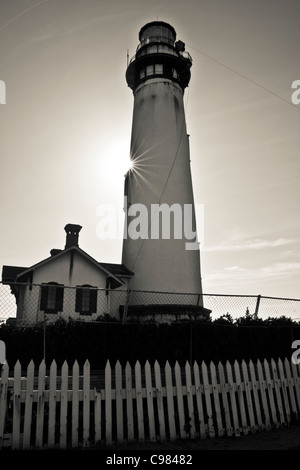 B&W von Pigeon Point Light Station südlich von San Francisco, Kalifornien, mit Sunburst, Lattenzaun, Objektiv-Schlitten und Seilrutschen. Stockfoto