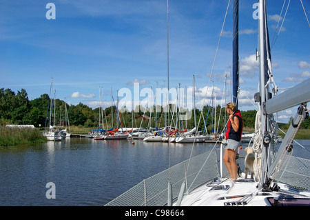 Frau und Hund auf einem Segelboot Annäherung an Pier am See Mälaren, in Schweden, an einem Sommertag. Stockfoto