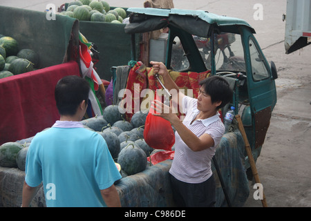 Mit einem Gewicht von Wassermelonen mit einer Waage Waage, Bauernmarkt, Jingzhou, China Stockfoto