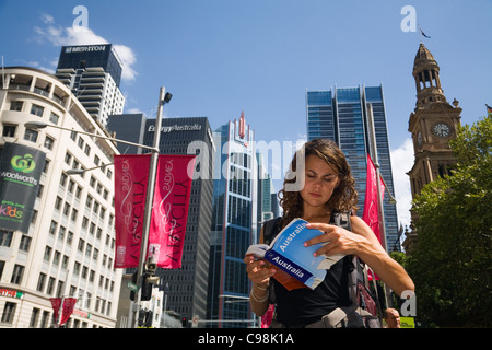 Backpacker Reiseführer mit Skyline der Stadt im Hintergrund zu lesen.  Sydney, New South Wales, Australien Stockfoto