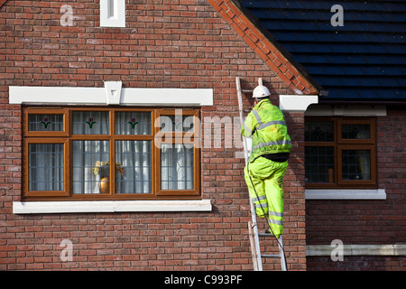 Männer auf Leitern Polystyrol Raupe Haus Wand Isolierung, Arbeiter in Sicherheit Kabelbaum installieren Schaum Isolierung in Southport, Großbritannien Stockfoto