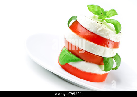Tomate und Mozzarella Scheiben verziert mit Basilikum-Blätter auf einem Teller und weißen Hintergrund Stockfoto