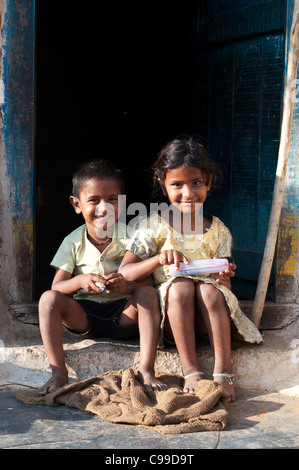 Lächelnd, glücklich Indianerdorf Mädchen und junge sitzt in der Tür ihres Hauses. Andhra Pradesh, Indien Stockfoto